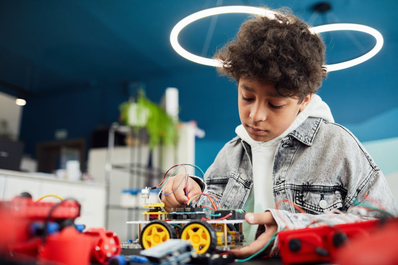 menu-10 A focused young boy works on a robotics project indoors, showcasing learning and innovation.