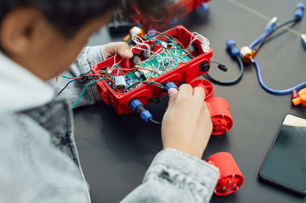 menu-06 A child actively assembling a robotics project with electronic components, showcasing technology education.