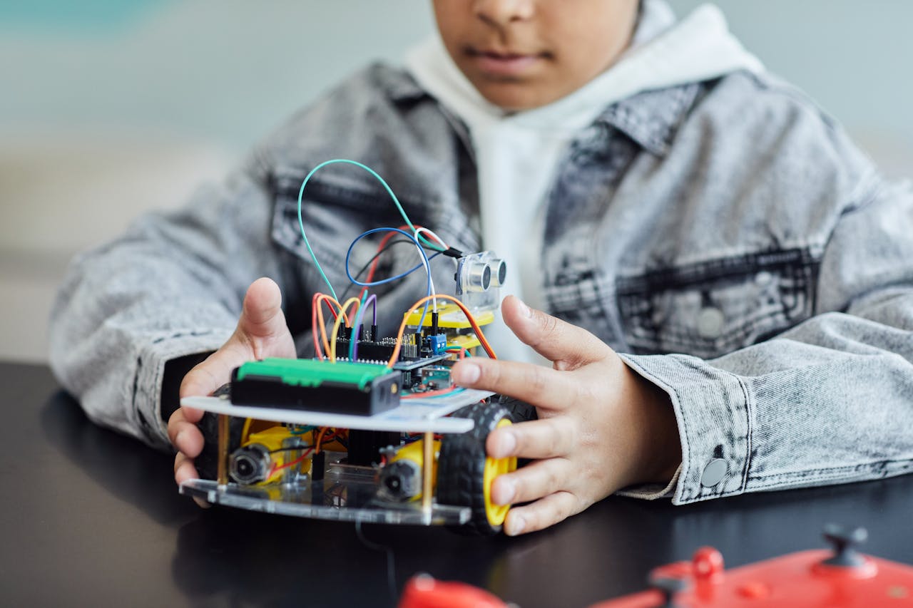 menu-04 A child working on a DIY robotics project with wires and wheels, showcasing innovation and creativity.